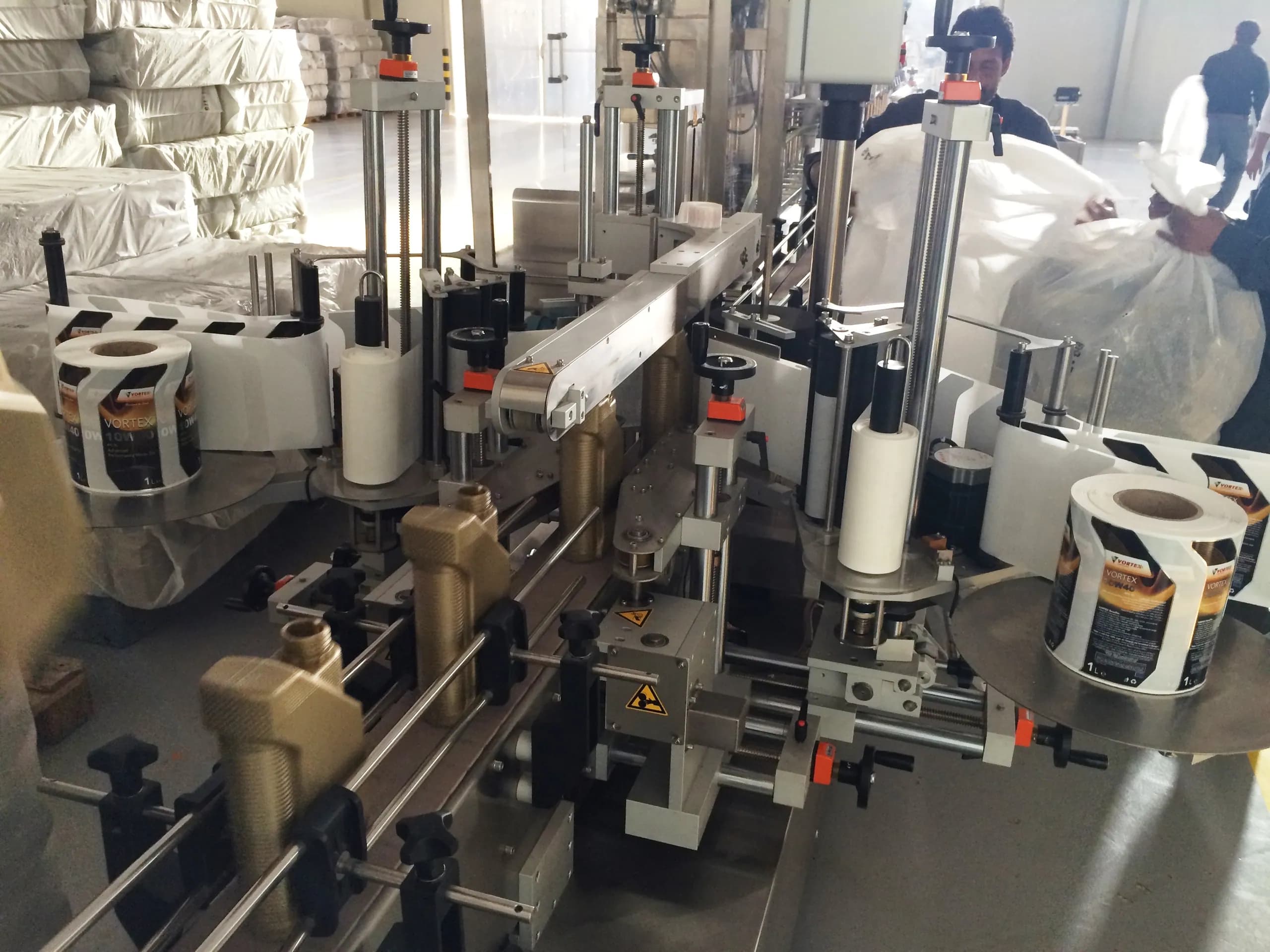 Labelling machine with reels of Vortex product labels mounted either side of the conveyor